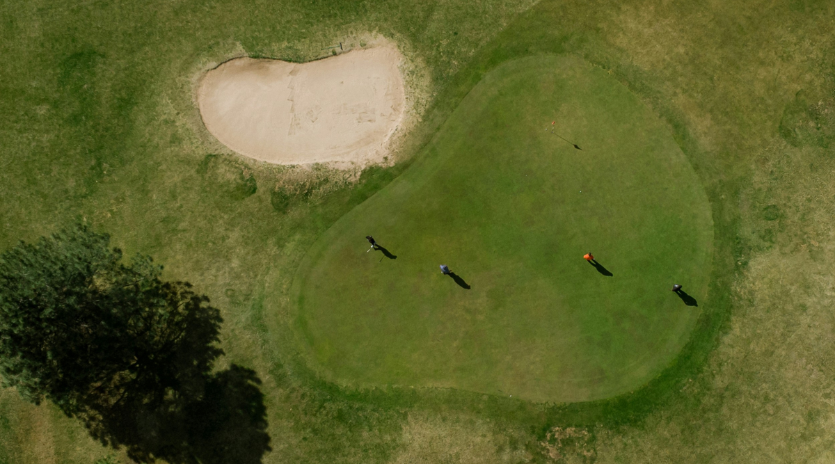 Four men on a golf course from overhead 